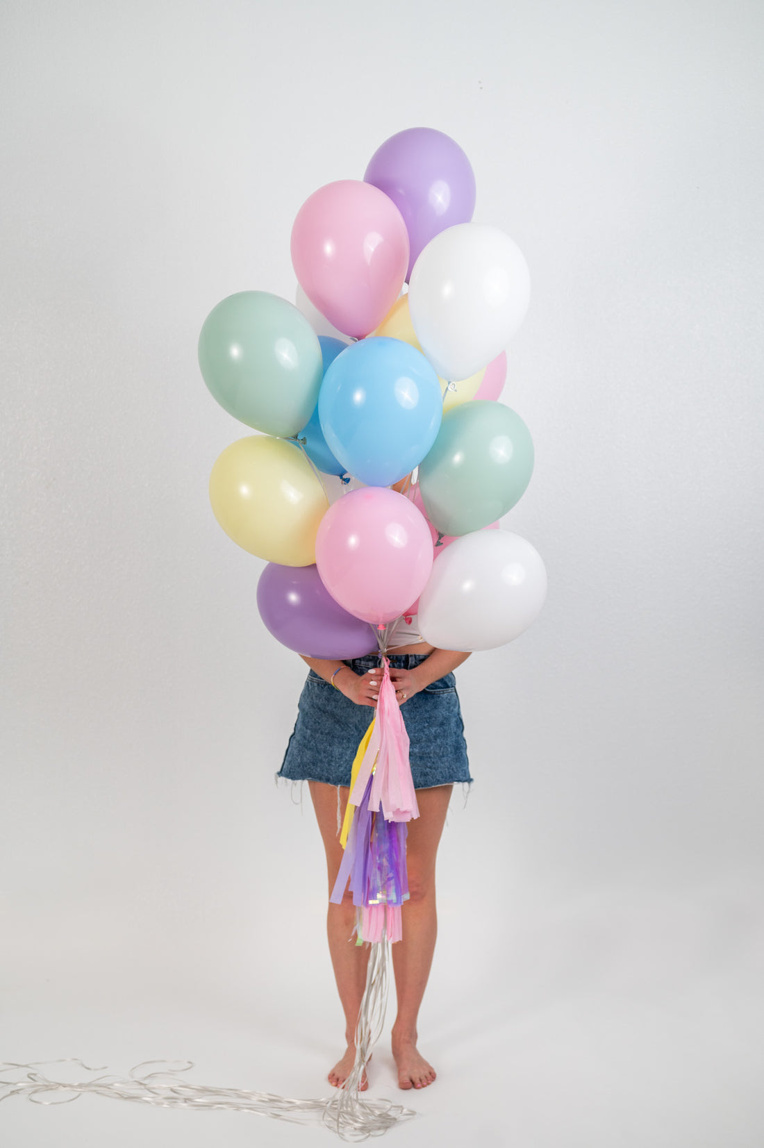 Person holding the pastel balloon bouquet in front of their face